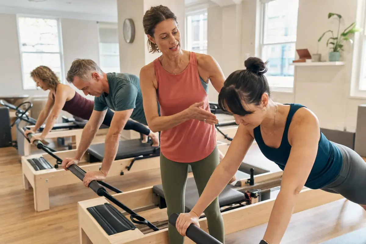 Pilates instructor guiding adults using reformer equipment in a UK studio